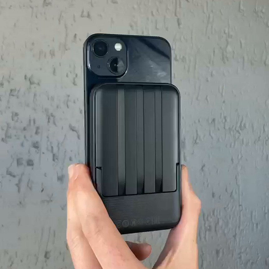 A hand holding a phone with the power bank snapped onto its back.