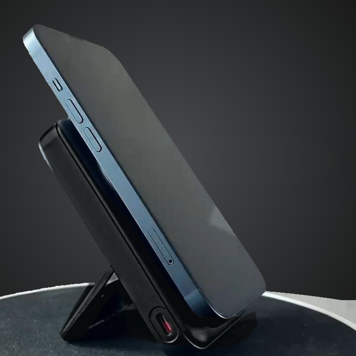 A phone held on the power bank by magnets and propped up on the fold-out stand.